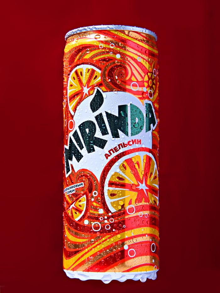 our-experience Colorful Mirinda orange soda can with vibrant design on a bold red background