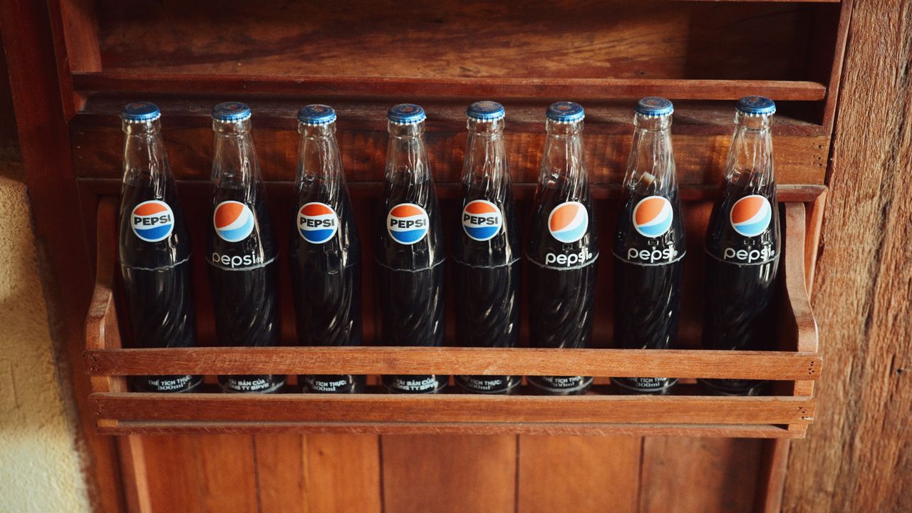A collection of vintage Pepsi bottles showcased in a rustic wooden rack.