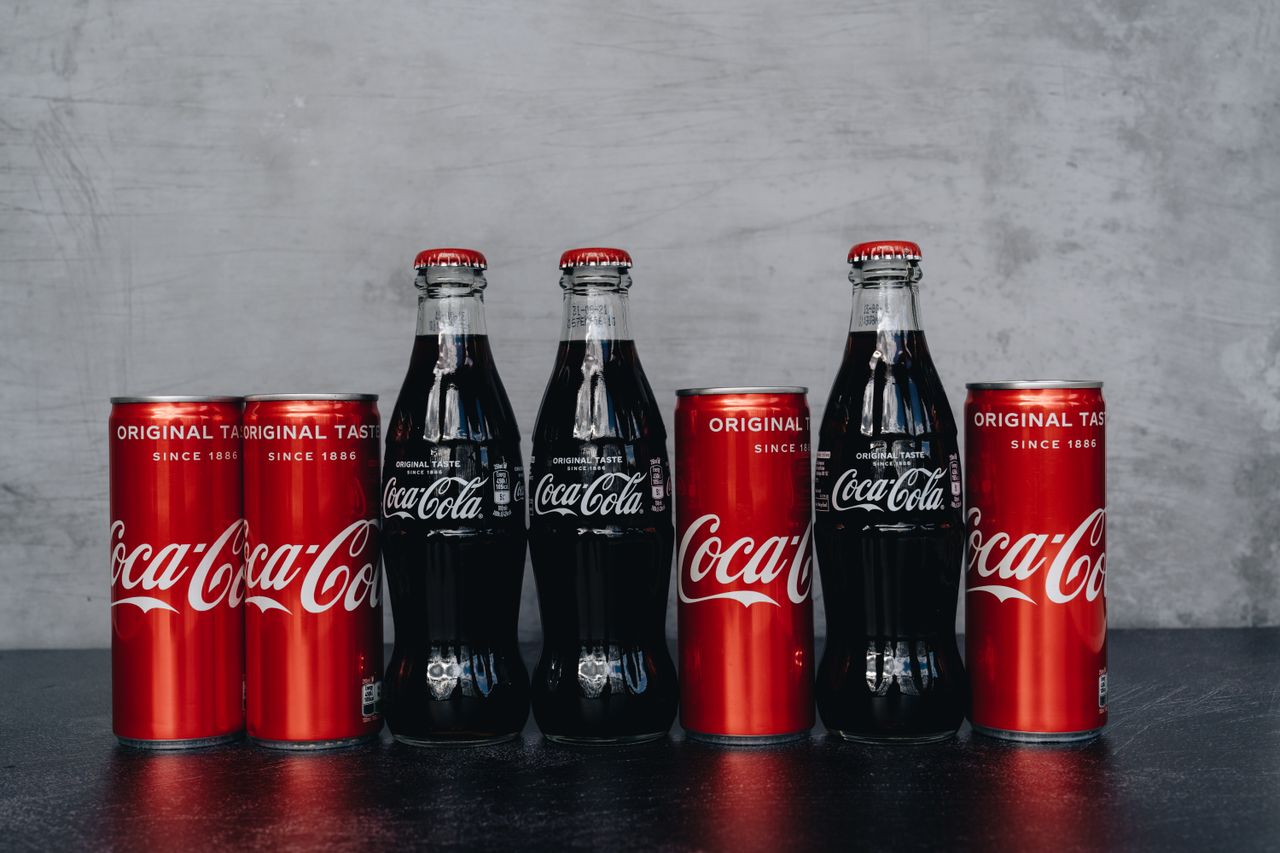 A lineup of Coca Cola bottles and cans representing the classic and refreshing brand image.