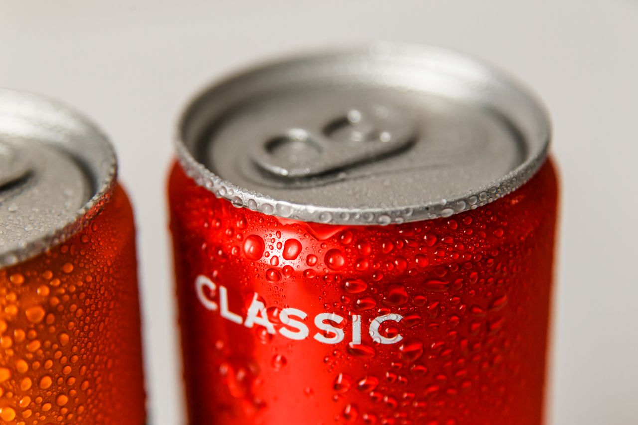 about-02 Refreshing close-up of wet red and orange soda cans with condensation droplets.