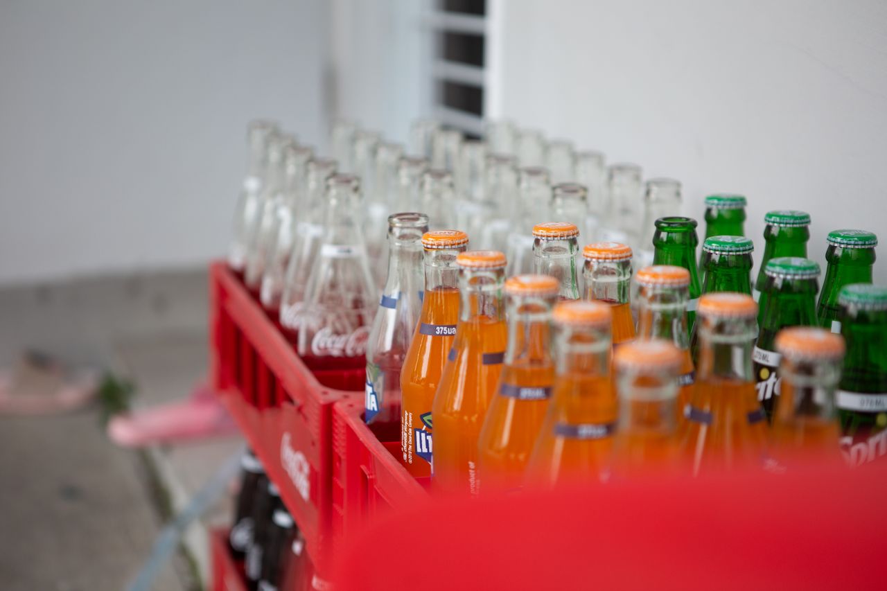 services-04 A collection of various bottled soft drinks in red crates, showcasing vibrant colors and popular brands.